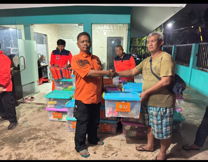 Komandan Pleton Satgas BPBD Tangsel Dian Wiriyawan memberikan bantuan sembako bagi warga terdampak banjir